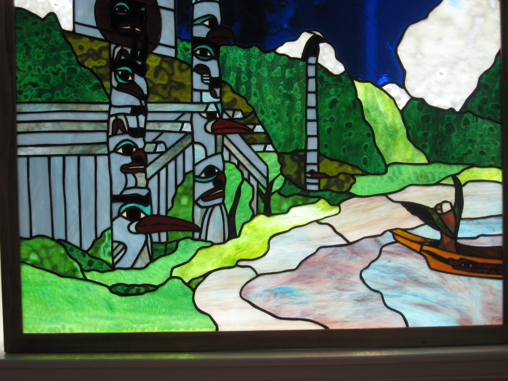 Totem poles next to a beach with a canoe